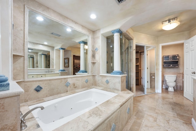 bathroom featuring sink, decorative columns, toilet, and tiled tub