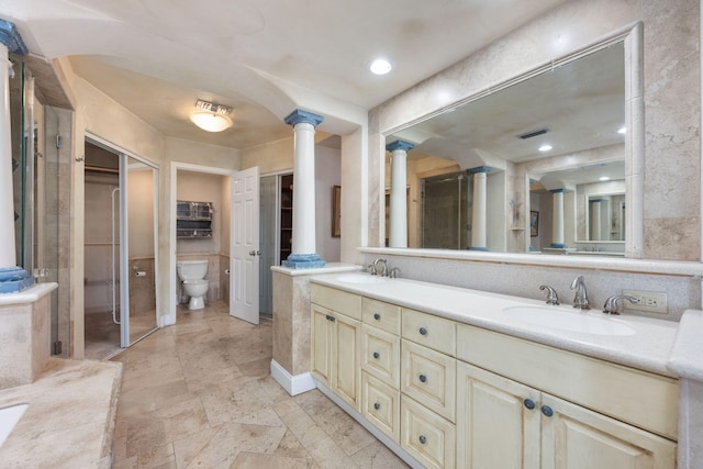 bathroom with ornate columns, vanity, and toilet