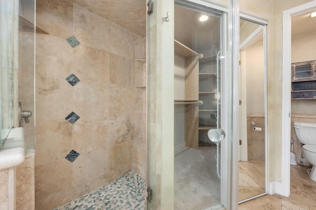 bathroom featuring an enclosed shower, toilet, and tile walls