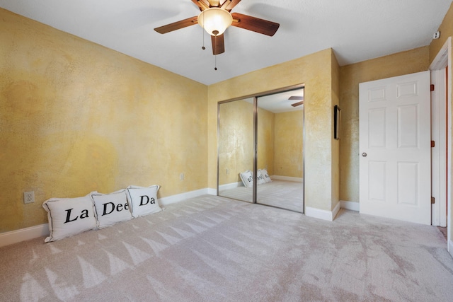 unfurnished bedroom featuring ceiling fan, a closet, and light colored carpet