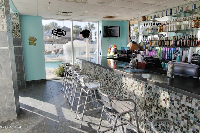 bar featuring a drop ceiling and a wall of windows