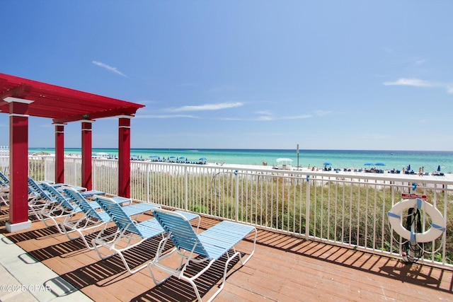 wooden deck with a water view and a beach view