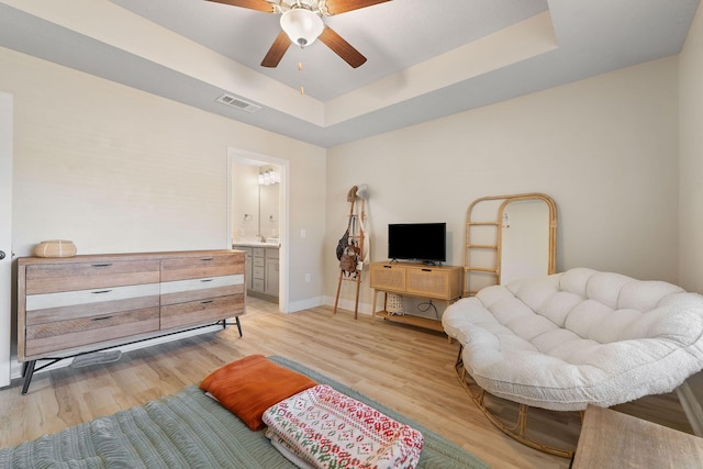 living room featuring ceiling fan, light hardwood / wood-style floors, and a tray ceiling