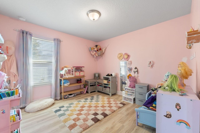 playroom featuring light hardwood / wood-style floors and a textured ceiling