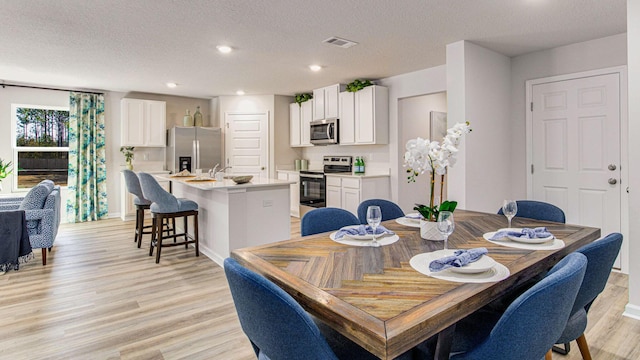 dining space with a textured ceiling and light hardwood / wood-style floors