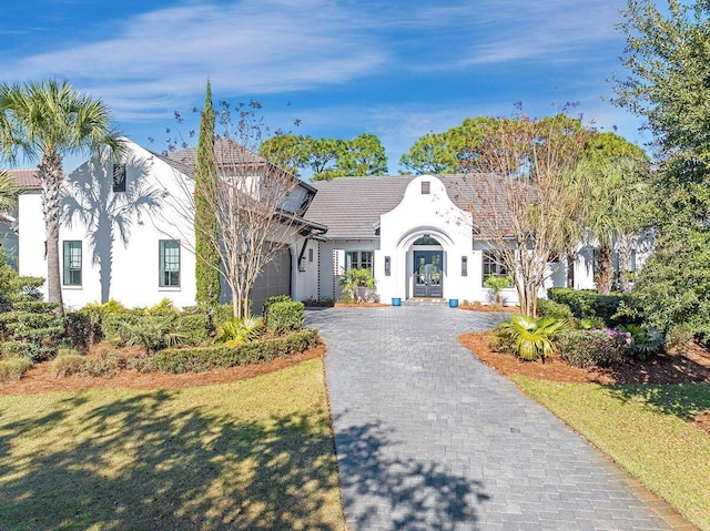 view of front facade with french doors, a garage, and a front lawn