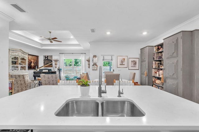 kitchen featuring sink, crown molding, and an island with sink