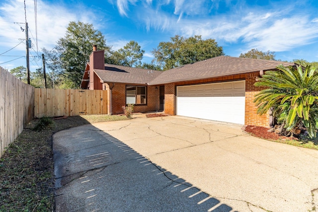 view of front of house featuring driveway, a chimney, an attached garage, fence, and brick siding