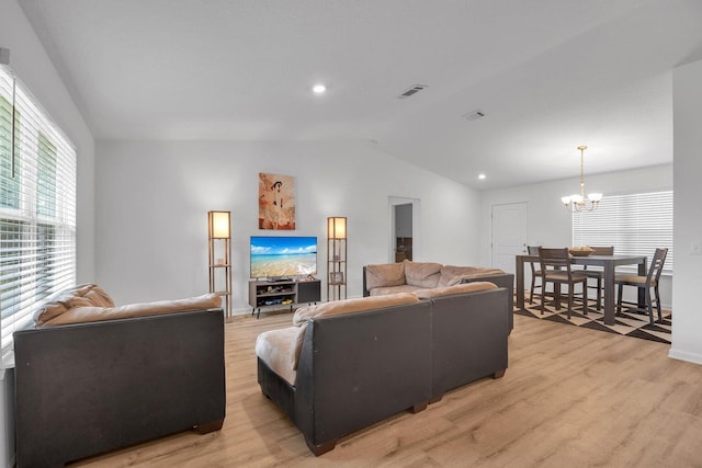 living room with a notable chandelier, light wood-type flooring, and vaulted ceiling