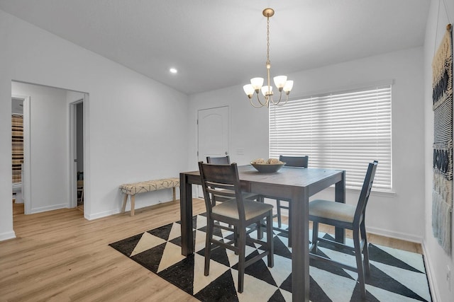 dining area with a chandelier, lofted ceiling, and light wood-type flooring