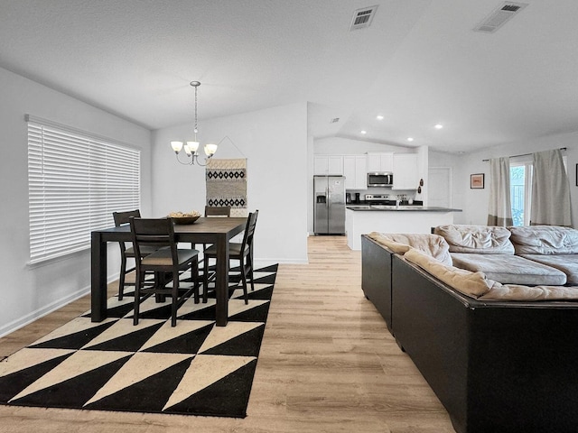 living room featuring light wood-type flooring, lofted ceiling, and an inviting chandelier