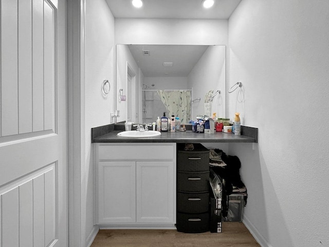 bathroom with hardwood / wood-style floors, vanity, and a shower