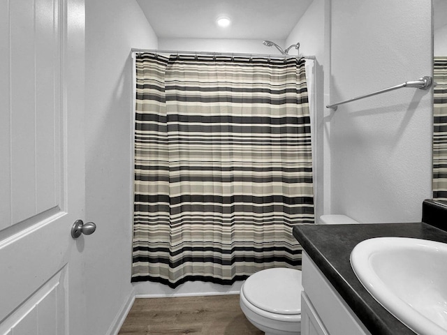 full bathroom featuring hardwood / wood-style floors, vanity, shower / tub combo, and toilet