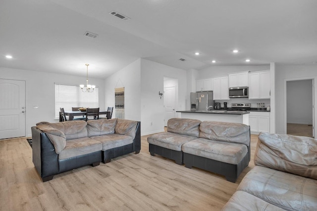 living room featuring a chandelier, light wood-type flooring, and vaulted ceiling