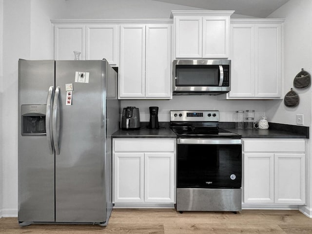 kitchen with appliances with stainless steel finishes, light hardwood / wood-style floors, white cabinetry, and lofted ceiling