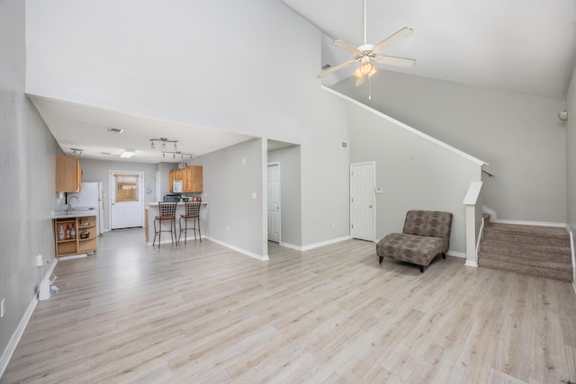 living area with ceiling fan, high vaulted ceiling, and light wood-type flooring