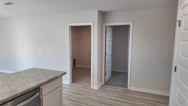 kitchen featuring white cabinets, beverage cooler, a textured ceiling, and light wood-type flooring