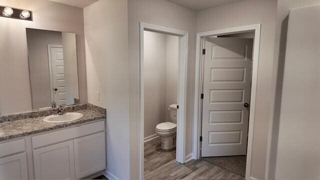 bathroom featuring hardwood / wood-style floors, vanity, and toilet