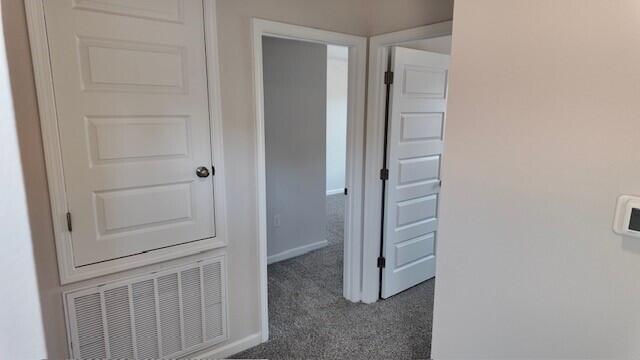 hallway featuring dark colored carpet