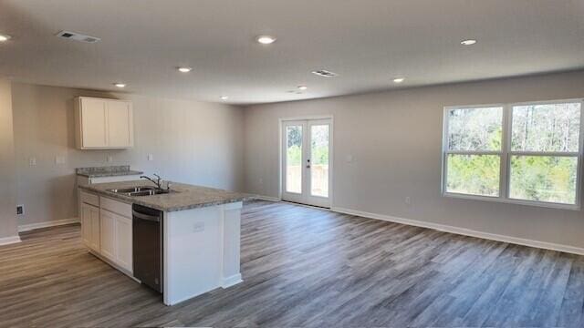 kitchen featuring dark wood-type flooring, sink, dishwasher, white cabinetry, and an island with sink