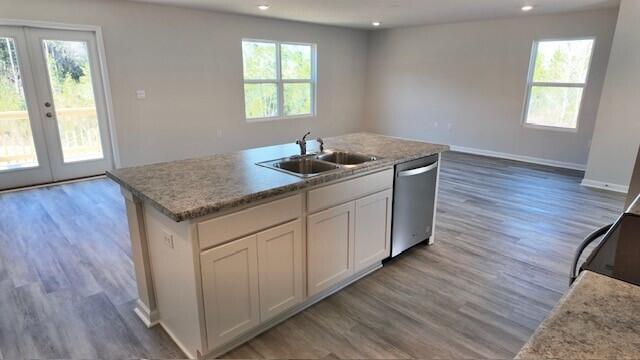 kitchen with french doors, sink, stainless steel dishwasher, a kitchen island with sink, and white cabinets