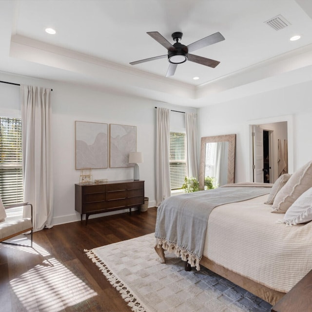 bedroom with dark hardwood / wood-style flooring, a raised ceiling, and ceiling fan