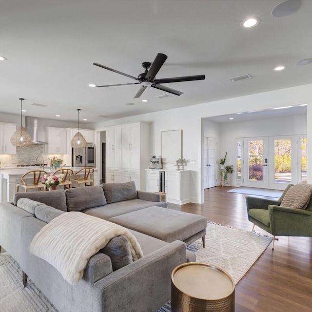 living room featuring wood-type flooring, sink, french doors, and ceiling fan