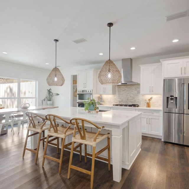 kitchen featuring wall chimney exhaust hood, white cabinetry, and stainless steel appliances