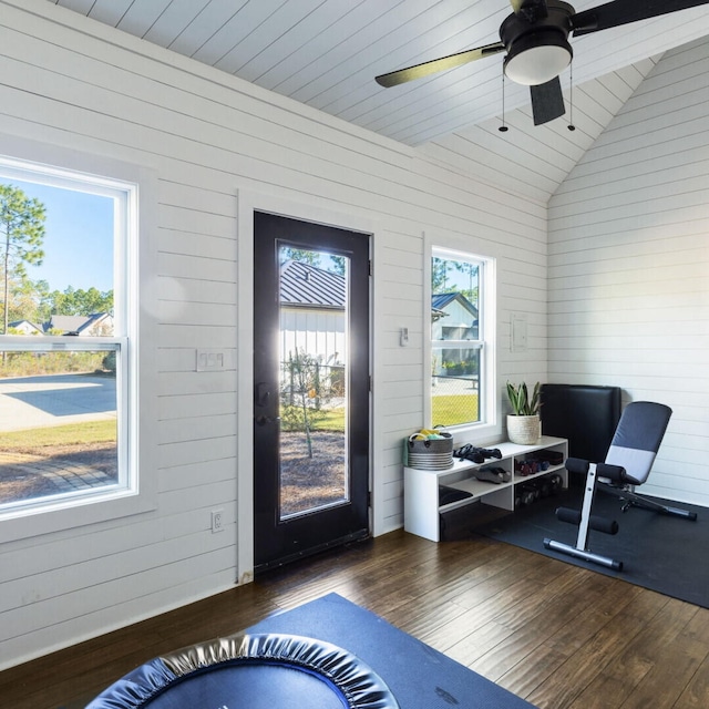 entryway with dark hardwood / wood-style floors, vaulted ceiling, ceiling fan, and wood walls