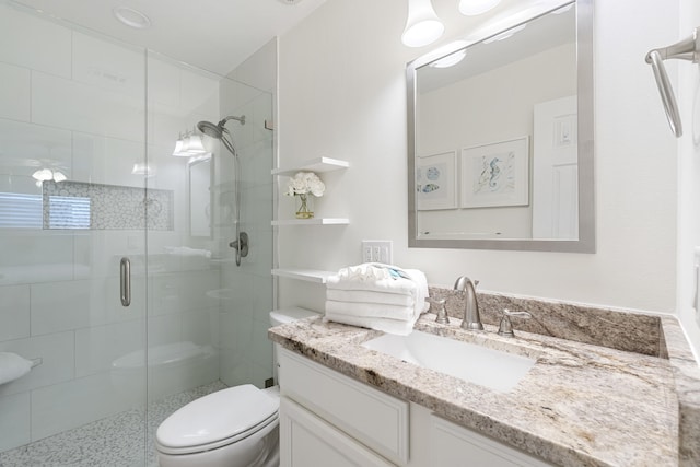 bathroom featuring an enclosed shower, vanity, and toilet