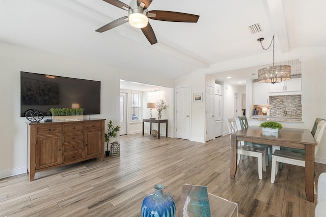 living room with lofted ceiling with beams, ceiling fan with notable chandelier, and light hardwood / wood-style flooring