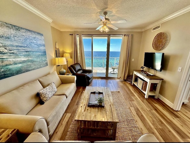 living room featuring hardwood / wood-style floors, a textured ceiling, ceiling fan, and crown molding