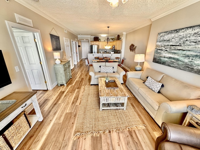 living room featuring light wood-type flooring, a textured ceiling, and ornamental molding