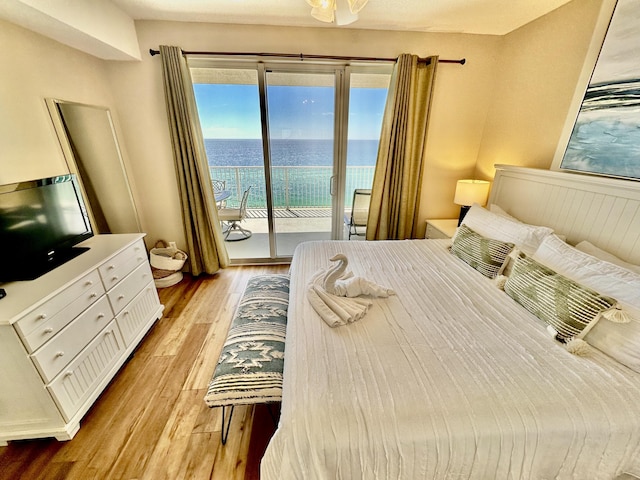 bedroom with access to exterior, a water view, and light hardwood / wood-style floors