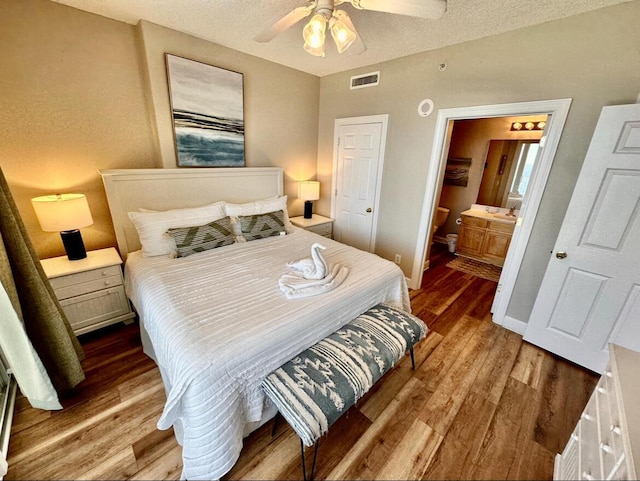 bedroom featuring a textured ceiling, dark hardwood / wood-style floors, ensuite bath, and ceiling fan