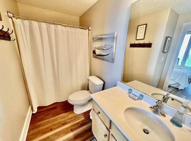 bathroom with hardwood / wood-style floors, vanity, toilet, and a textured ceiling