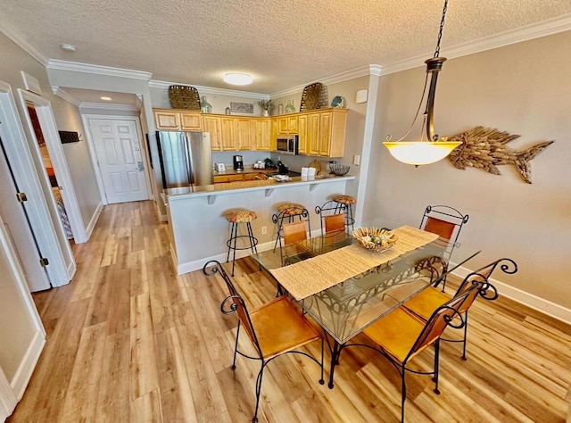 dining space featuring a textured ceiling, light hardwood / wood-style flooring, and ornamental molding