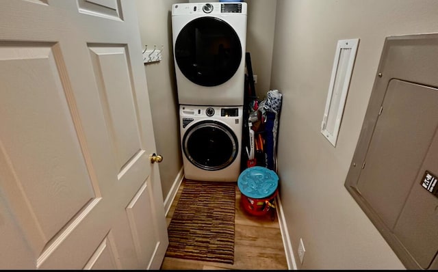 laundry room with electric panel and stacked washer and dryer