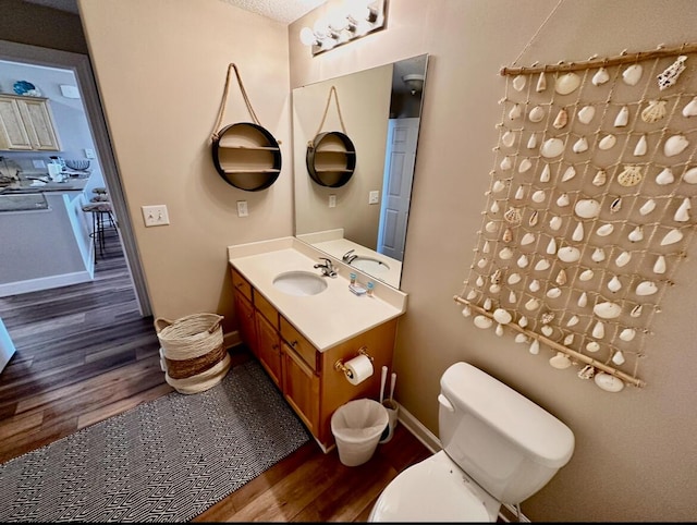 bathroom with vanity, toilet, wood-type flooring, and a textured ceiling