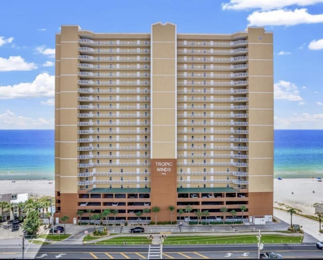 view of building exterior featuring a water view and a beach view