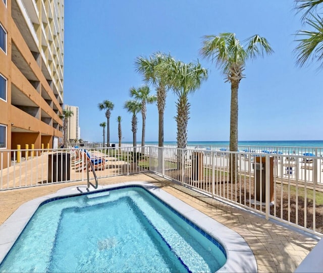 view of swimming pool featuring a view of the beach and a water view