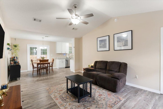 living room with ceiling fan, vaulted ceiling, and light wood-type flooring