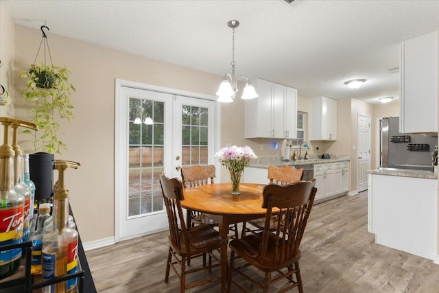 dining room featuring french doors, light hardwood / wood-style floors, a textured ceiling, and sink