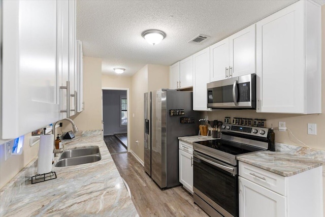 kitchen with appliances with stainless steel finishes, white cabinetry, and sink