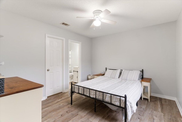 bedroom with a textured ceiling, ceiling fan, ensuite bathroom, and light hardwood / wood-style flooring