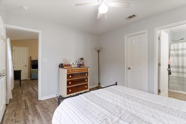 bedroom with a textured ceiling, ensuite bath, light hardwood / wood-style flooring, and ceiling fan