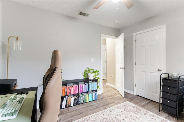 home office featuring ceiling fan, light hardwood / wood-style floors, and a textured ceiling