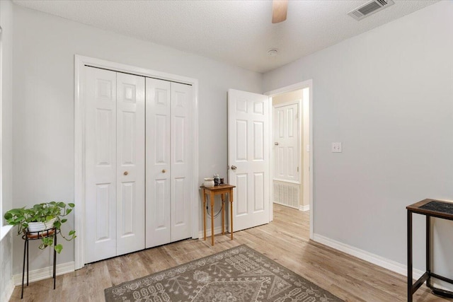 interior space featuring a textured ceiling, a closet, light hardwood / wood-style floors, and ceiling fan