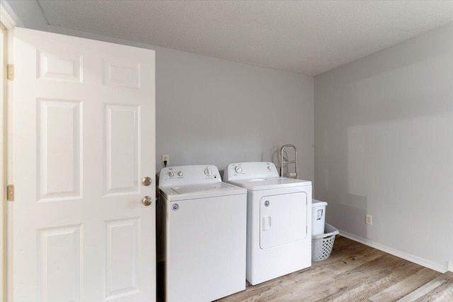 washroom featuring independent washer and dryer, light wood-type flooring, and a textured ceiling