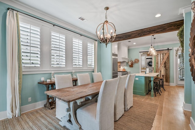 dining area with beamed ceiling, plenty of natural light, a barn door, and light hardwood / wood-style flooring